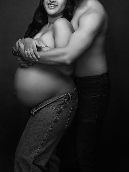 An intimate and raw black and white portrait of a couple, showcasing their connection and the beauty of the baby bump.
