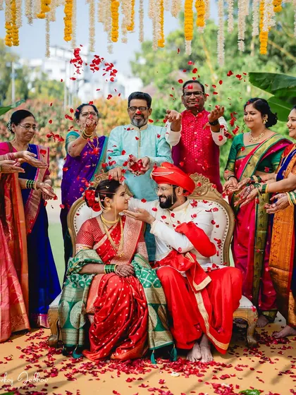 A wedding is not just about two people, but about two families coming together. Here, loved ones shower the couple with blessings and rose petals, creating a vibrant, joyful memory of a traditional Maharashtrian wedding ceremony.
