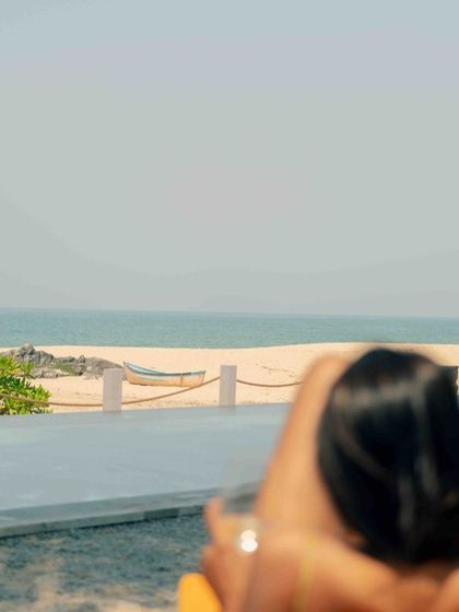 A guest relaxing by the beachside infinity pool at The Postcard Arabian Sea, a perfect picture of tranquility and a high-end beach getaway.
