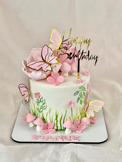 A lovely cake for a fiancée, featuring a hand-painted garden scene with pink flowers, mushrooms, and fluttering butterflies for a touch of enchantment.