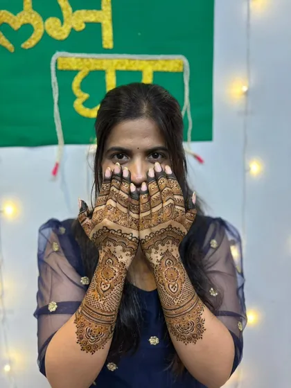 The bride playfully hiding her face, giving a full view of her gorgeous half-hand mehendi.