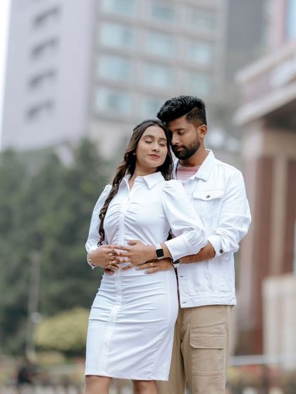 A romantic portrait of a couple embracing in an urban setting, with the soft focus on the city buildings in the background.