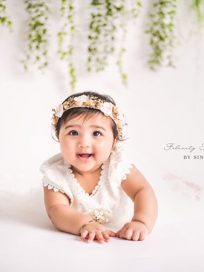 A pure bundle of joy during her sitter session. The simple white backdrop and hanging greenery put all the focus on her adorable expression and bright eyes.