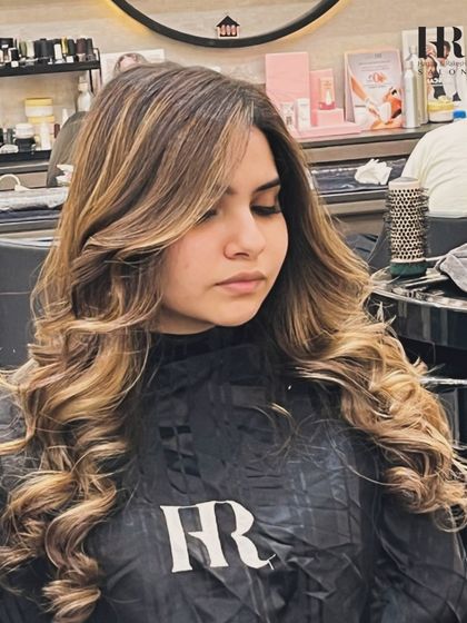 A close-up of a client with a fresh balayage and blowout, showing the face-framing pieces and soft layers.