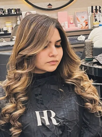 A close-up of a client with a fresh balayage and blowout, showing the face-framing pieces and soft layers.