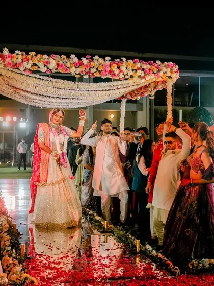 A full view of the bride's stunning entry under a phoolon ki chadar on a mirrored aisle, a truly glorious moment.