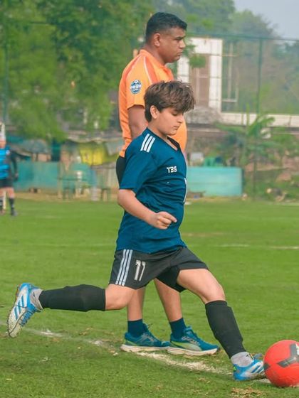 A young player takes a corner kick under the watchful eye of a coach, preparing to set up a scoring opportunity for his team.