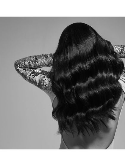 A simple yet glamorous shot focusing on texture and light. The backless top with shimmering sequin sleeves contrasts with the model's dark, flowing hair, creating a beautiful study in monochrome.