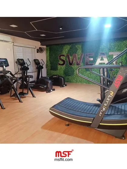 The cardio area at Sweat Park, featuring our self-powered curve treadmill. This machine is a centerpiece, offering a unique and challenging workout that sets a gym apart.
