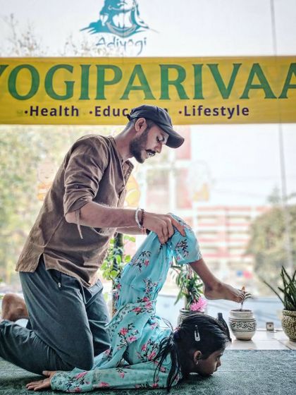 An instructor helps a child with a gentle backbend, improving spinal flexibility and strength.