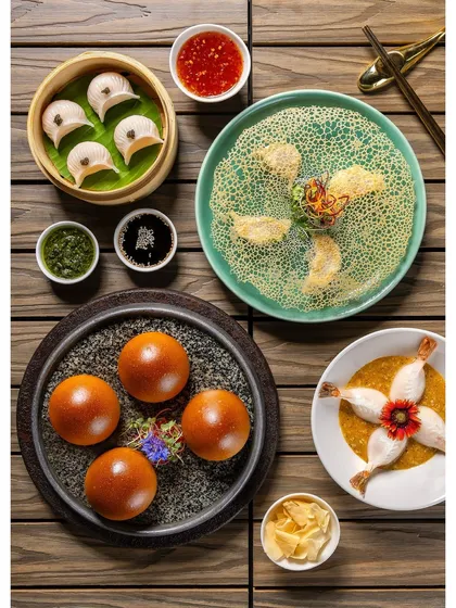 A flat lay of assorted non-vegetarian dim sum for the Shang Palace menu. This shot displays the variety of shapes and fillings, from buns to dumplings.