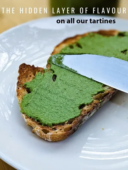 Spreading the vibrant green coriander pesto on a slice of crusty sourdough bread.