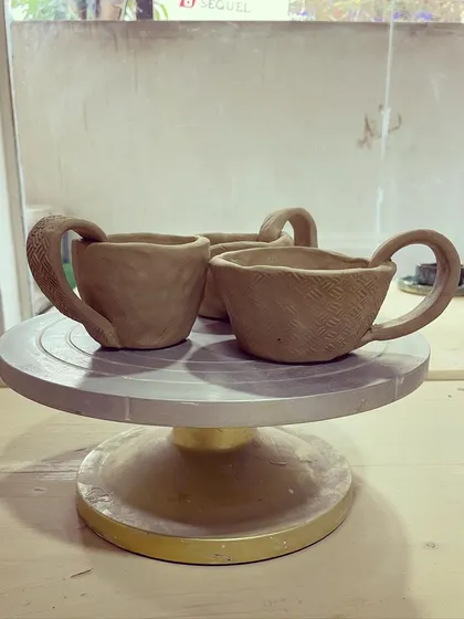 A set of three charming, rustic cups, each with its own unique texture, all made using the hand-building pinch method.