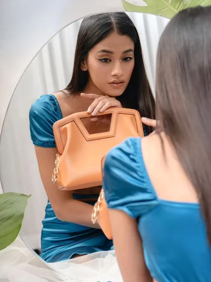 A creative studio shot for Sarjaa using a mirror to create depth. The model's reflection adds a layer to the story, showcasing the handbag from multiple perspectives.