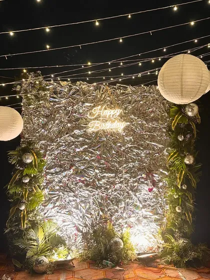 A shimmery and fun birthday backdrop we created for a rooftop party. The silver foil curtain, neon sign, and paper lanterns created a festive and glamorous photo corner.