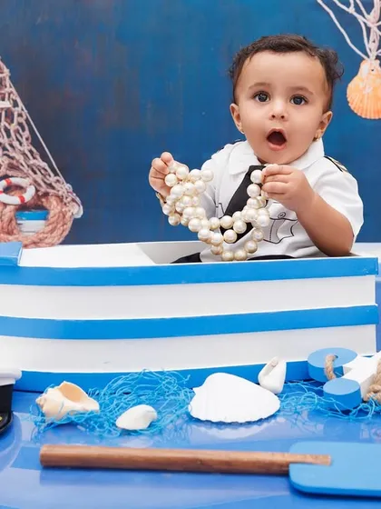 A little sailor discovers treasure! A one-year-old boy finds a string of pearls in his nautical-themed setup.