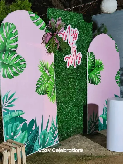A fun, tropical 'Miss to Mrs' theme. This setup uses panels with monstera leaf prints against a faux grass wall, creating a vibrant and trendy backdrop for a bachelorette party or bridal shower.