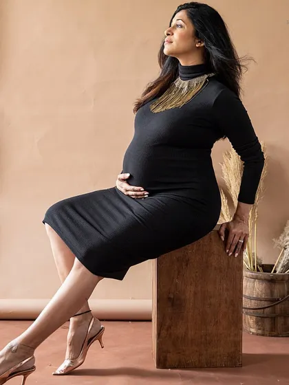 A classic and elegant pose in a simple black dress. The gold necklace adds a touch of glamour to this sophisticated studio portrait.