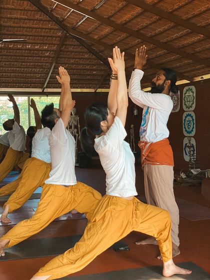 In a group setting, I still provide individual adjustments. Here, I guide a student to find more length and lift in Virabhadrasana I (Warrior I), helping them feel the full expression of the pose.