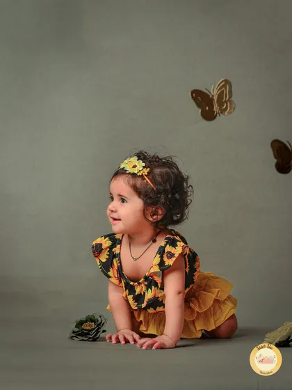 A beautiful butterfly-themed session. The sunflower headband and golden butterflies create a whimsical, nature-inspired setting for this crawling baby.