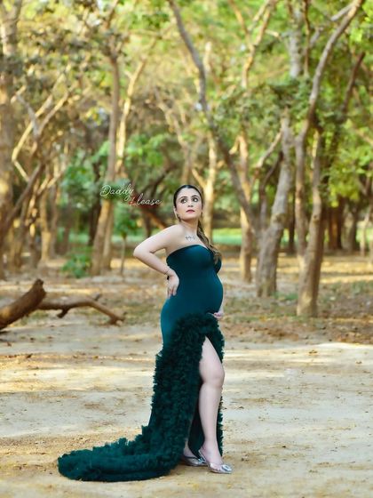 A confident pose from an outdoor pregnancy session. The mother-to-be looks powerful and beautiful in her green gown, surrounded by the rustic charm of the woods.