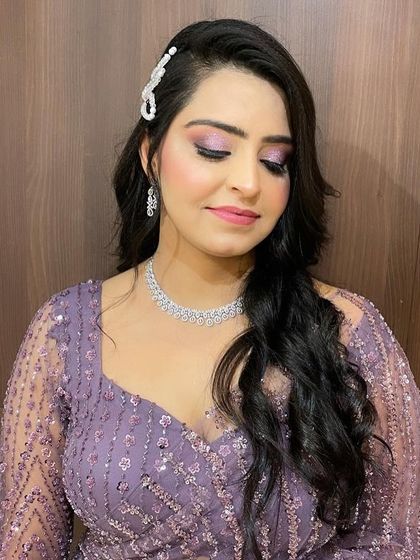 A glamorous side-swept hairstyle with voluminous waves, perfect for a wedding reception or cocktail party. The look is completed with a sparkling hair accessory.