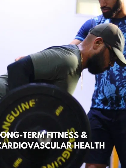 We focus on long-term fitness and cardiovascular health. A coach provides support during a heavy lift, illustrating our commitment to helping you build sustainable strength and a healthy heart.