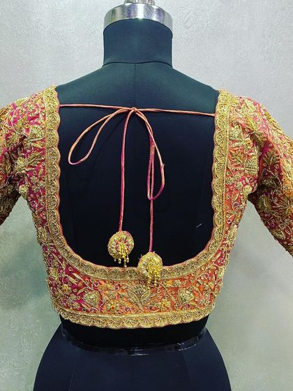 This blouse has a wide square back, fully bordered with heavy Zari and thread embroidery. The simple dori and small tassels keep the focus on the detailed handwork.