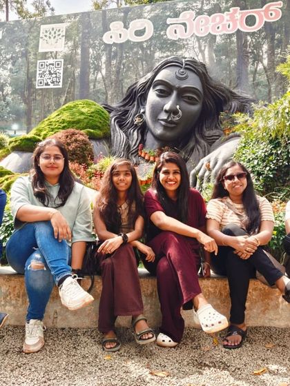 A group of friends posing in front of the Adiyogi statue at a nature resort near Chikmagalur. It's a popular spot for a memorable photo.