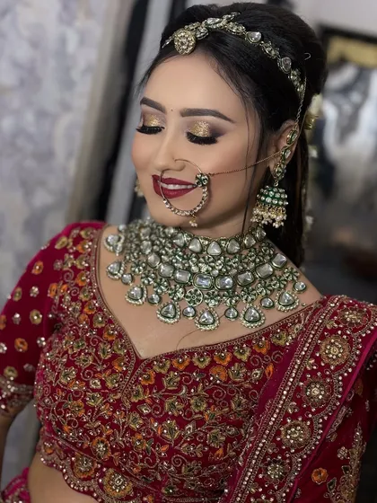 A close-up on the eyes. This image highlights the golden glitter eyeshadow and bold red lip, a classic combination for a traditional Indian bride in a red lehenga.