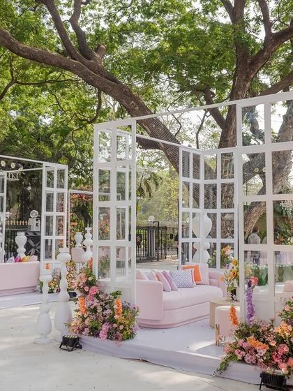 The "Bloom" wedding seating arrangement is a study in floral elegance and timeless charm. The modern white structures provide a clean backdrop for the colorful flowers and chic pink furniture.