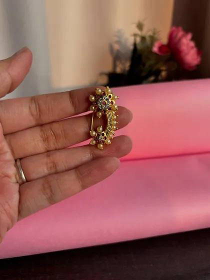 A still image of the beautiful floral clip-on Nath, held in hand to show its size and delicate design.