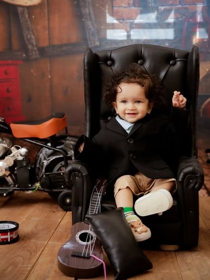 A future rockstar in the making. This setup includes a mini leather chair, a toy motorcycle, and a drum set for a cool and edgy baby portrait.