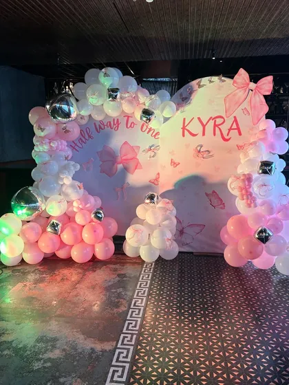 The bow-themed backdrop illuminated by colorful party lights, creating a fun and celebratory mood.