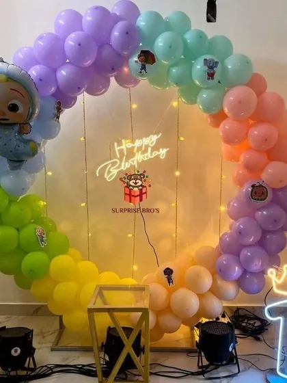 A Cocomelon-themed circular balloon arch in rainbow pastel colors, perfect for a first birthday photo backdrop.