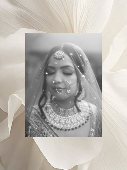 A beautiful black and white portrait of a bride under her veil, her eyes closed, framed by a white floral border.