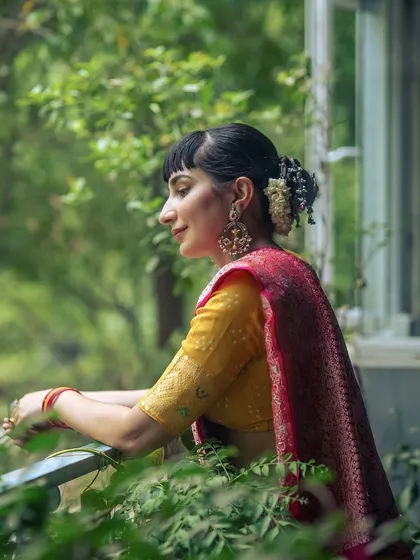 A profile shot enjoying a moment of calm, with the traditional gajra and jewellery complementing the beautiful saree.