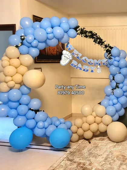A 'Welcome Baby Boy' decoration with a circular balloon arch in shades of blue and cream.