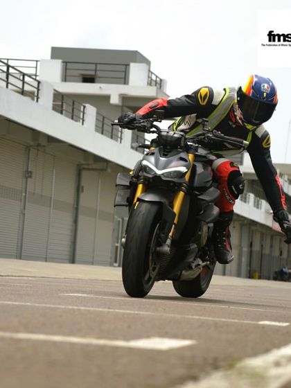 A rider showing off some style on their Ducati Streetfighter in the pit lane. It's a day for fun and expressing your passion.