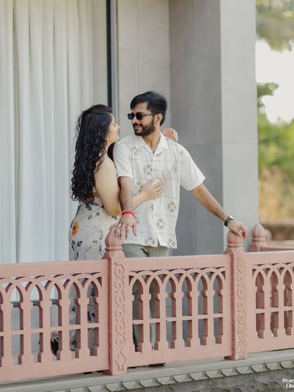 A sweet, candid moment on a balcony. This pre-wedding photo captures the couple's relaxed and happy interaction, showcasing their natural chemistry.