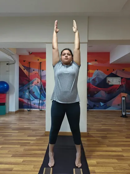 We begin with the basics. A student practices Tadasana (Mountain Pose) on her toes, engaging her leg muscles and finding her center of balance. This simple pose is the foundation for all standing postures.
