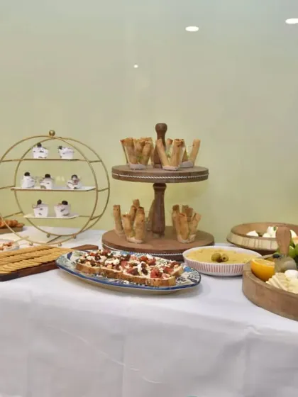 A wide view of the complete grazing table setup for Clinic Dermatech. The clean white tablecloth and wooden serveware create a fresh and modern look.