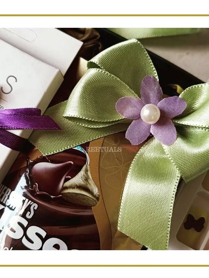The final touch on a bridesmaid gift. A beautiful satin bow with a floral and pearl accent, showing the elegant packaging that makes each gift feel special.