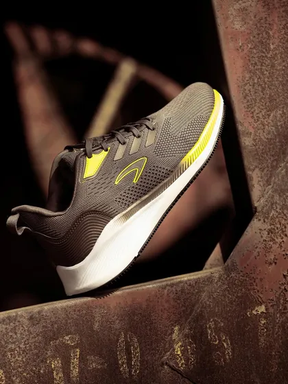 A running shoe placed on a rusty metal beam. The contrast between the modern, clean sneaker and the decaying industrial environment creates a powerful, gritty image.