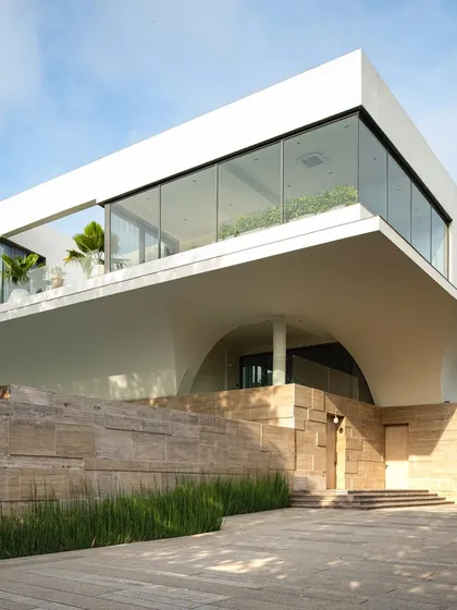 The minimalist landscape of Project Priyam. Here, a strong architectural form is softened by a simple palette of native grasses and a striking travertine-clad wall, demonstrating how restraint in design can achieve maximum impact.