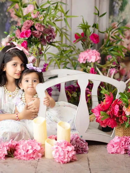 A lovely portrait of two sisters in a beautiful, floral-themed studio setup. This setting is perfect for creating whimsical and classic children's photos.