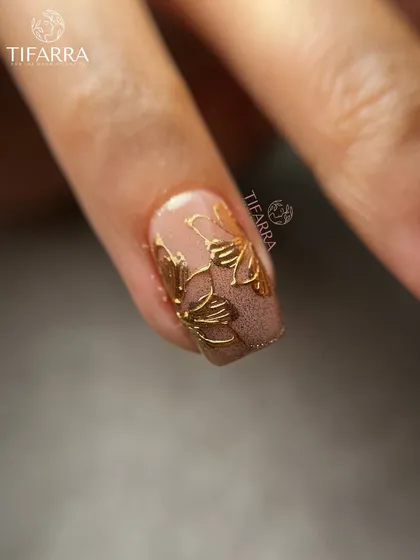 A close-up of our hand-drawn gold floral art on a matte, textured brown base, showcasing the versatility of our designs.