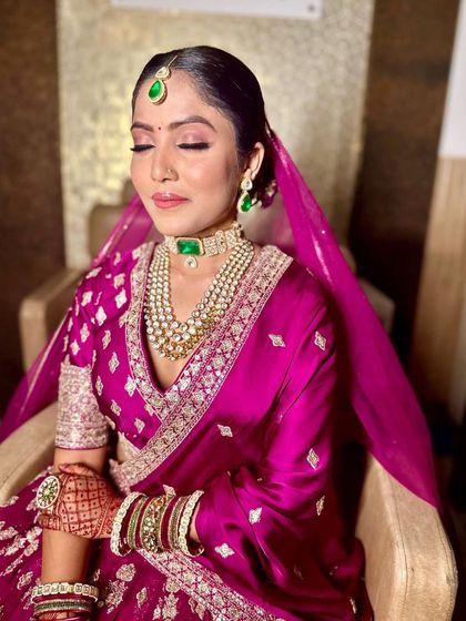 Draped in opulent pink and adorned with emerald accents, this bride embodies timeless allure. We paired her saree with a clean, elegant makeup look and a classic floral bun.