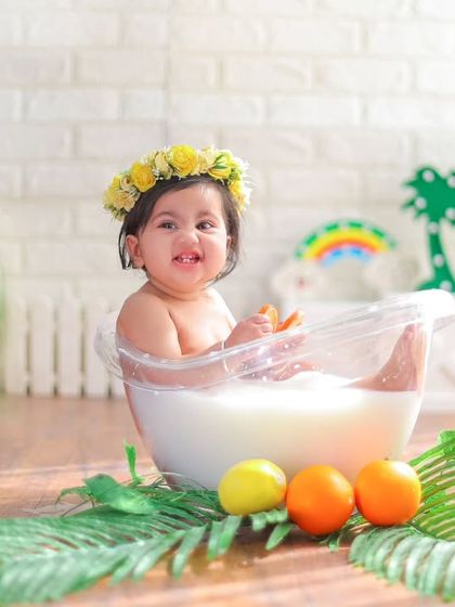 This wider shot of the milk bath setup shows the playful and tropical-inspired details, from the rainbow in the back to the palm leaves.