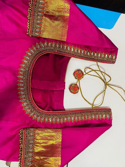 A pink blouse with a simple gold border design. The sleeves feature a patch of the original saree border for a perfectly matched set.